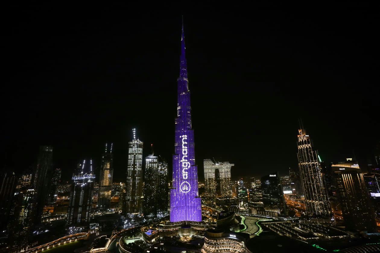 Burj Khalifa lit up in purple with the Anghami logo at night